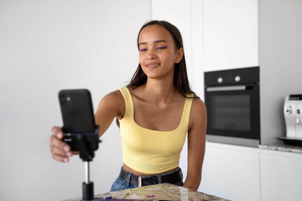 Joven grabando video con smartphone para redes sociales en su cocina