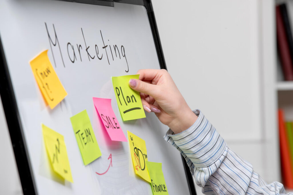 Persona organizando un plan de marketing con notas adhesivas en una pizarra
