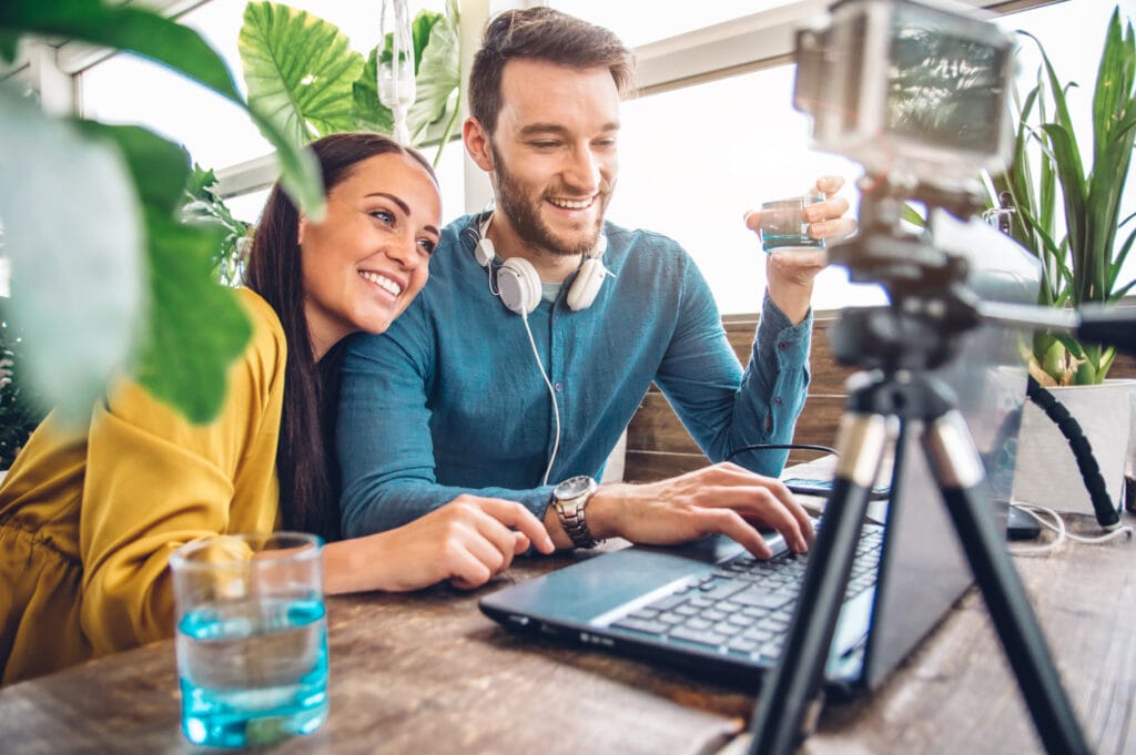 Feliz pareja de bloggers grabando un video preparándose para publicar