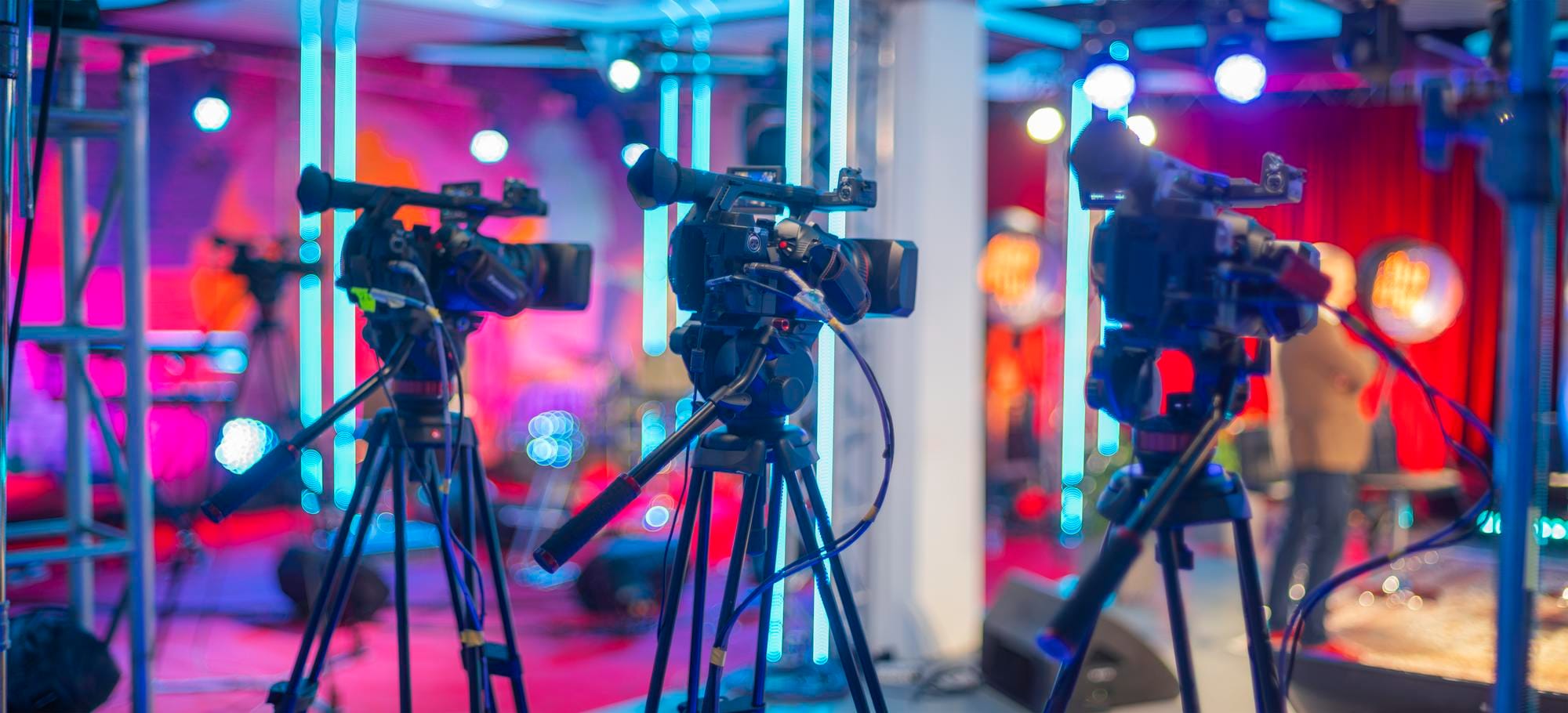 Cámaras de video en un set de grabación con luces brillantes y fondo colorido