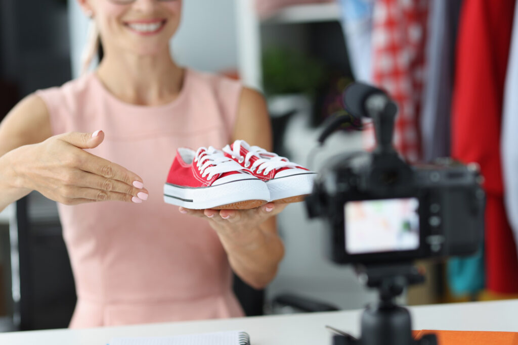 Consultor de vendedor de mujer muestra a la cámara zapatos deportivos rojos. Elección de los niños del concepto de calzado deportivo.