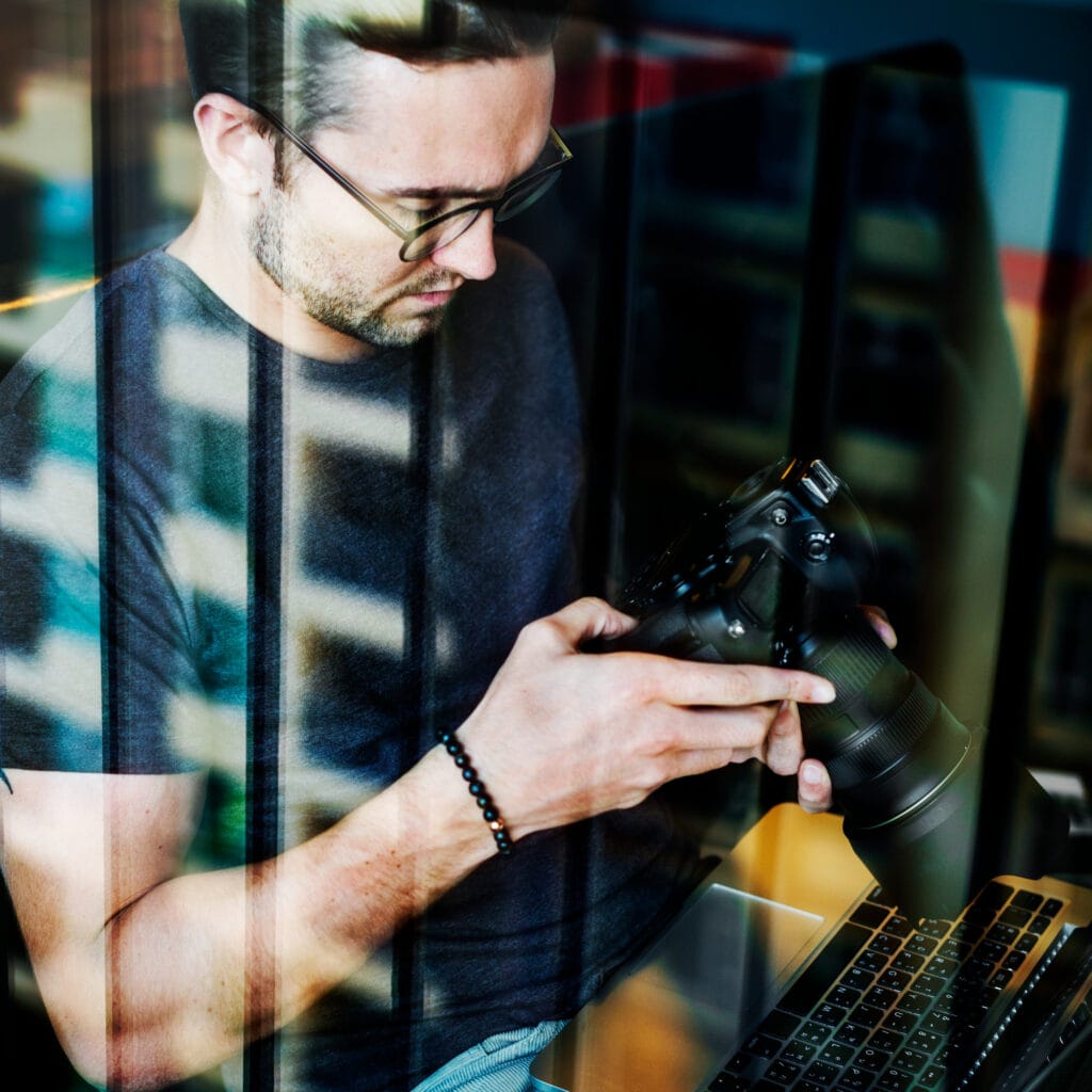Fotógrafo revisando cámara digital profesional frente al ordenador