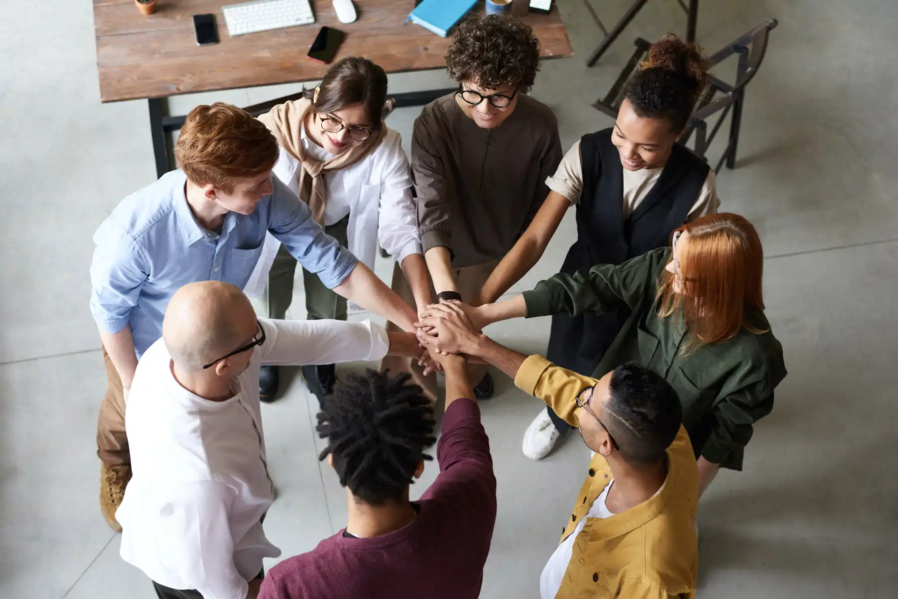 Grupo diverso de personas uniendo sus manos en señal de colaboración en un ambiente de trabajo moderno