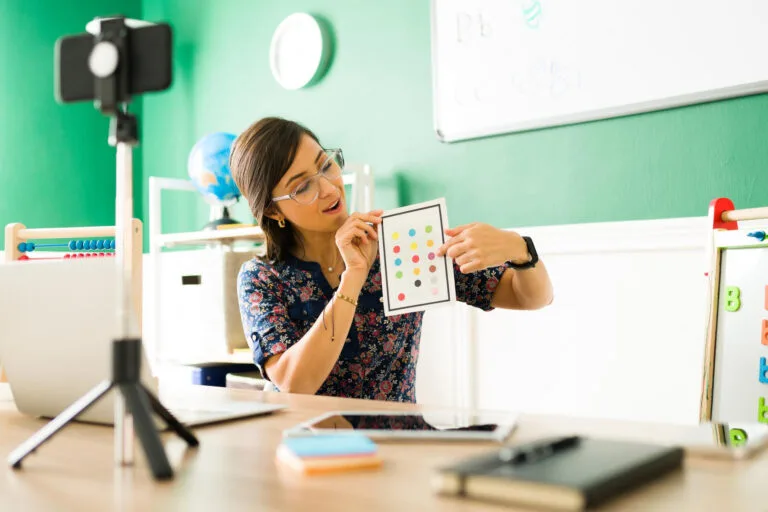 Maestra de preescolar usando tarjetas para enseñar los colores a los niños. Niños de jardín de infantes aprendiendo en una clase virtual