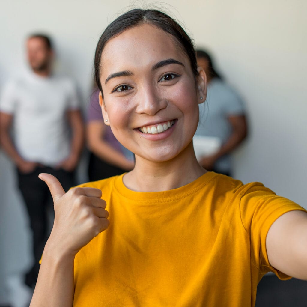 Mujer joven sonriente haciendo gesto de aprobación con el pulgar hacia arriba