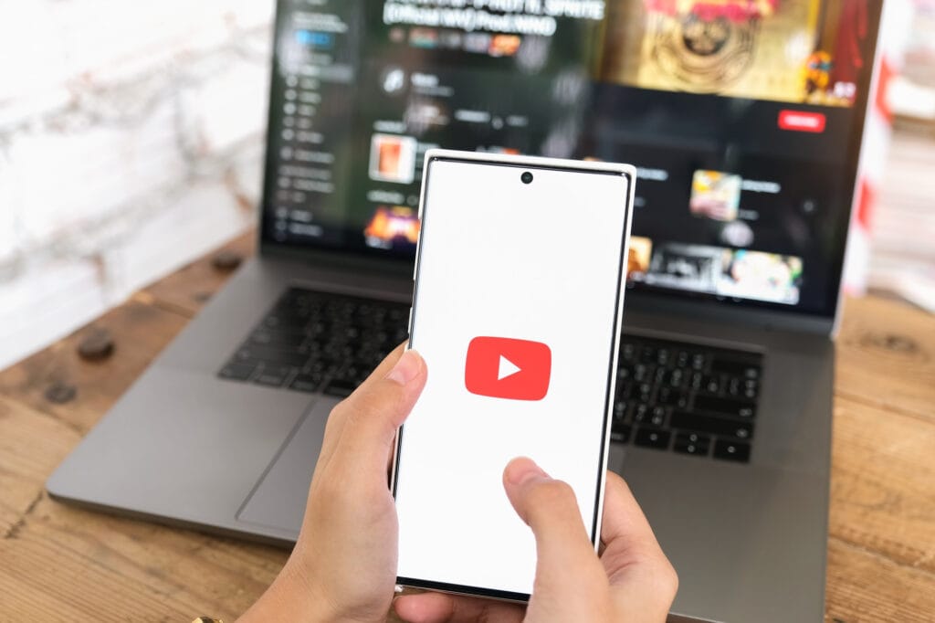 Mujer sosteniendo móvil smartphone con servicio de video YouTube en la pantalla