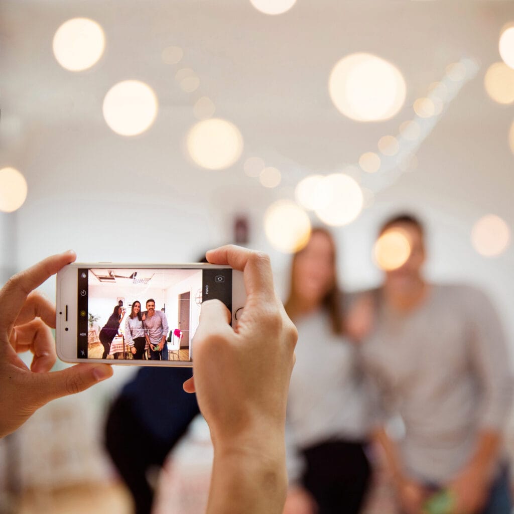 Persona tomando una foto grupal con smartphone en una fiesta